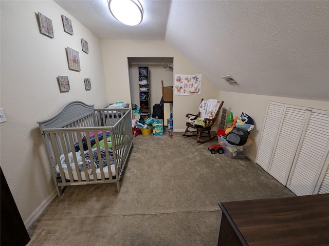 bedroom featuring a nursery area, visible vents, a textured ceiling, carpet, and vaulted ceiling