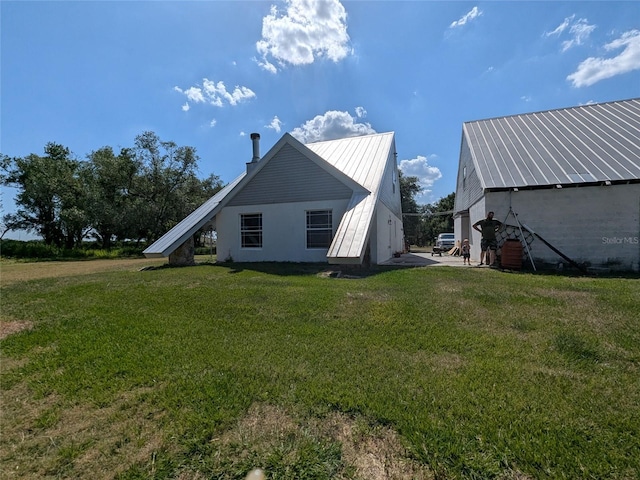 rear view of house with a lawn and metal roof