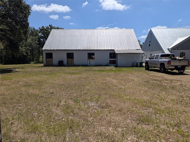 exterior space with a yard, an outbuilding, metal roof, and stucco siding