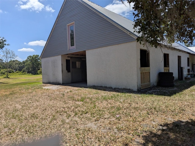 view of side of home featuring stucco siding and a yard