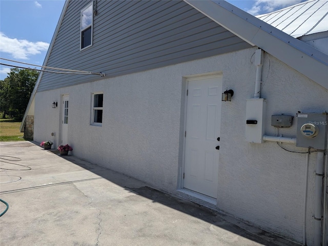 rear view of house featuring a standing seam roof, metal roof, a patio area, and stucco siding