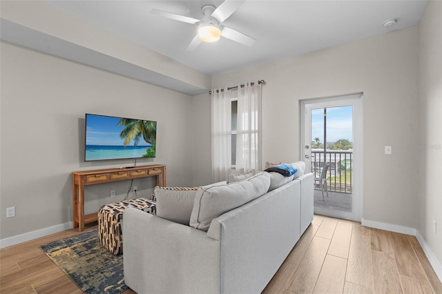 living room with light wood-type flooring, ceiling fan, and baseboards