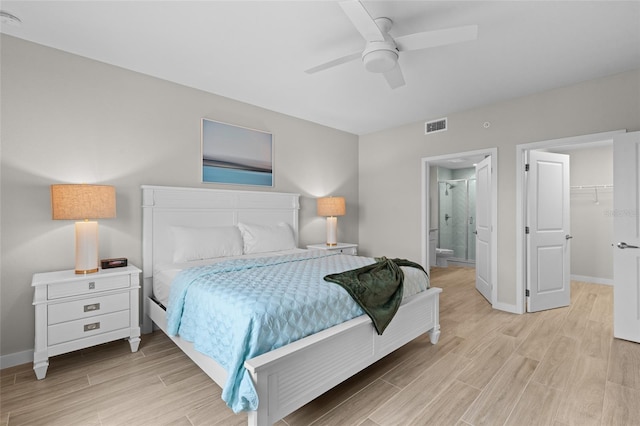 bedroom featuring light wood-style flooring, baseboards, connected bathroom, a walk in closet, and ceiling fan