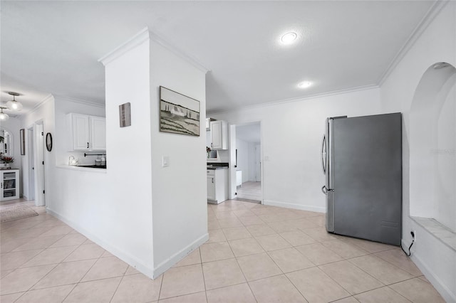 1741 NE Trisha Dr, Arcadia, FL 34266 - kitchen with freestanding refrigerator, crown molding, white cabinetry, light tile patterned flooring, and arched walkways