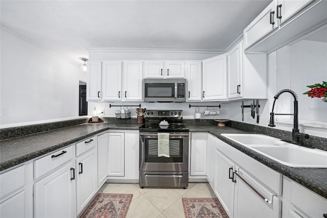1741 NE Trisha Dr, Arcadia, FL 34266 - kitchen featuring appliances with stainless steel finishes, a sink, white cabinetry, light tile patterned floors, and dark countertops