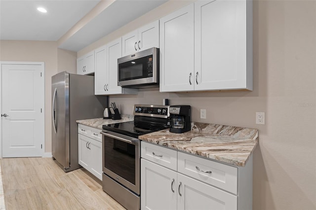 kitchen with stainless steel appliances, light wood finished floors, white cabinets, light stone countertops, and recessed lighting