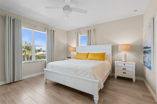 bedroom featuring light wood-style flooring, baseboards, and a ceiling fan