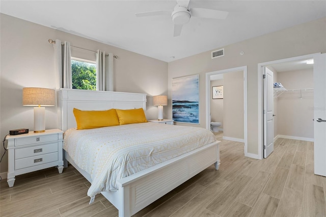 bedroom featuring light wood-type flooring, a closet, baseboards, a spacious closet, and a ceiling fan