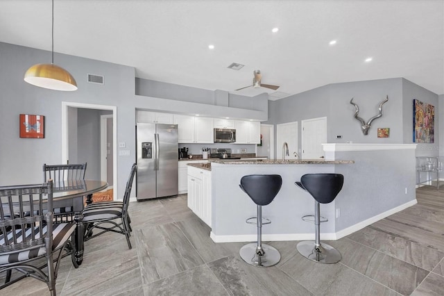 3520 Caya Largo Ct, Punta Gorda, FL 33950 - kitchen with visible vents, a breakfast bar, white cabinetry, a sink, and stainless steel appliances