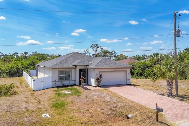 ranch-style house featuring driveway, a garage, fence, a shingled roof, and stucco siding