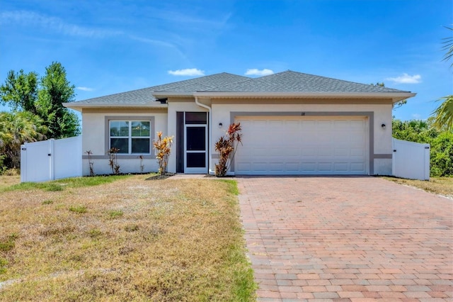 view of front of property featuring fence, a front yard, decorative driveway, stucco siding, and an attached garage