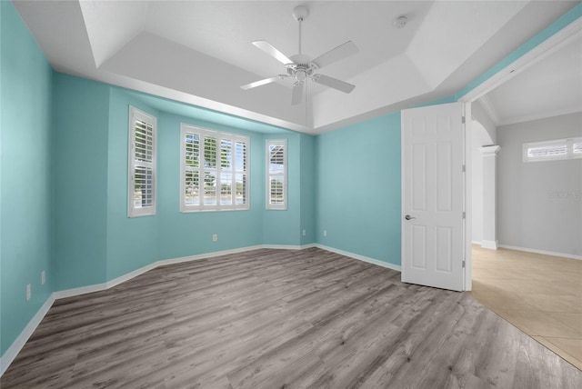spare room with a healthy amount of sunlight, ceiling fan, a tray ceiling, and wood finished floors