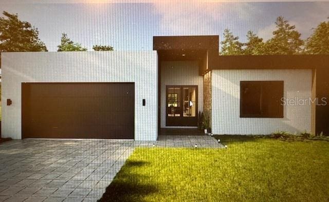 view of front of home with a garage, decorative driveway, and a front lawn