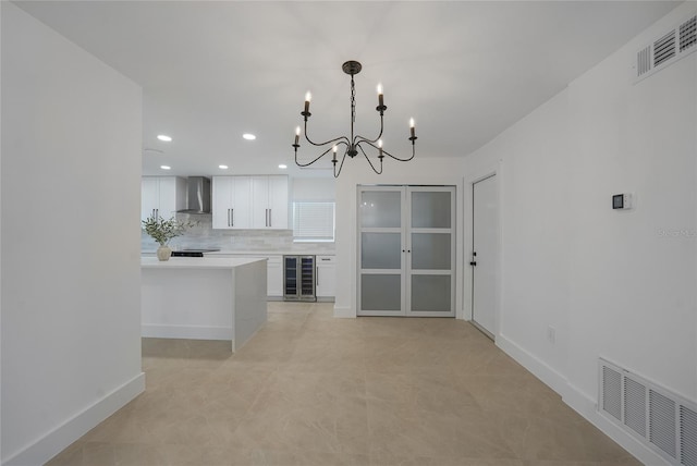 27385 Voyageur Dr, Punta Gorda, FL 33983 - kitchen featuring wine cooler, wall chimney range hood, a chandelier, light countertops, and white cabinetry