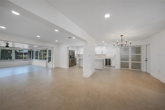 27385 Voyageur Dr, Punta Gorda, FL 33983 - unfurnished living room featuring a chandelier, a ceiling fan, recessed lighting, baseboards, and beverage cooler