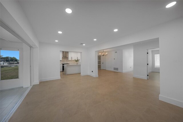 27385 Voyageur Dr, Punta Gorda, FL 33983 - unfurnished living room with a chandelier, plenty of natural light, baseboards, and recessed lighting