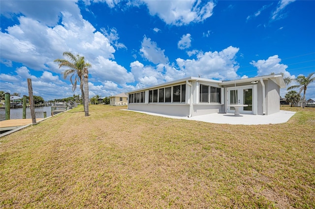 27385 Voyageur Dr, Punta Gorda, FL 33983 - rear view of house featuring a sunroom, a patio area, a lawn, and a water view