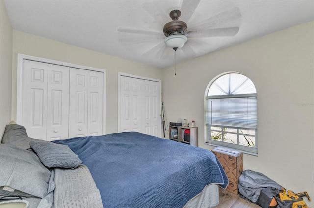 bedroom with multiple closets, ceiling fan, and wood finished floors