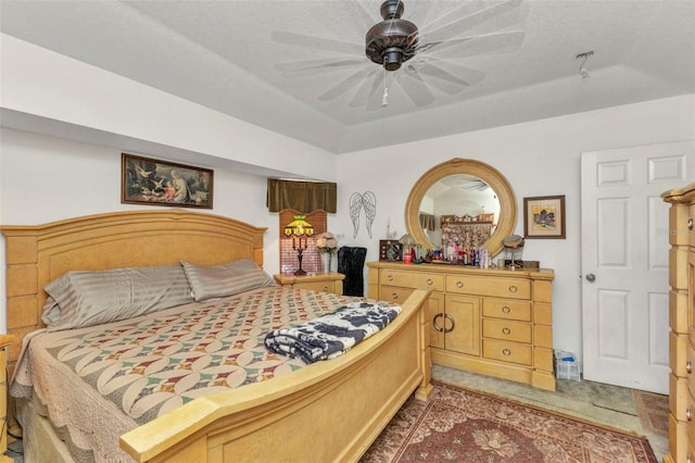 bedroom with a raised ceiling, ceiling fan, and light colored carpet