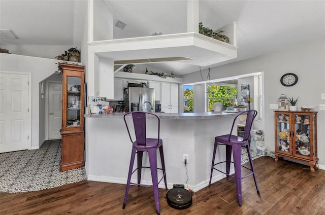 kitchen with dark wood-style flooring, a peninsula, lofted ceiling, a breakfast bar, and stainless steel fridge with ice dispenser