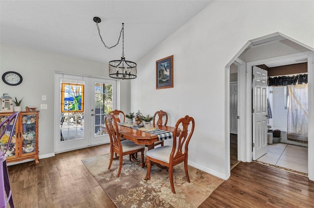 dining room with arched walkways, an inviting chandelier, wood finished floors, and vaulted ceiling