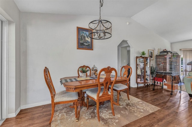 dining room with arched walkways, vaulted ceiling, wood finished floors, baseboards, and a chandelier