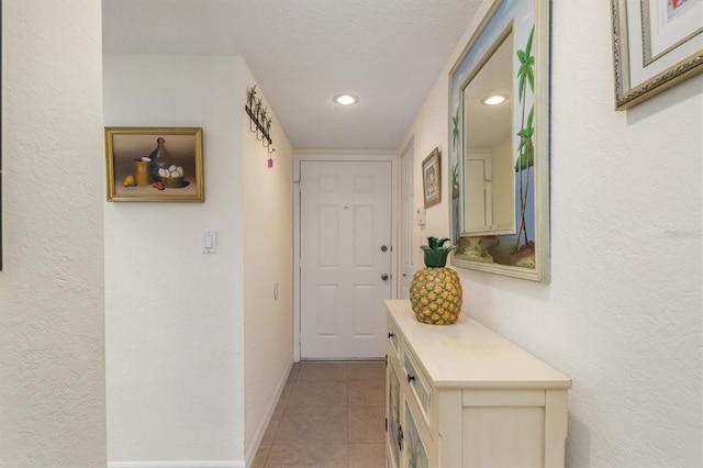 hallway with recessed lighting, baseboards, light tile patterned floors, and a textured ceiling