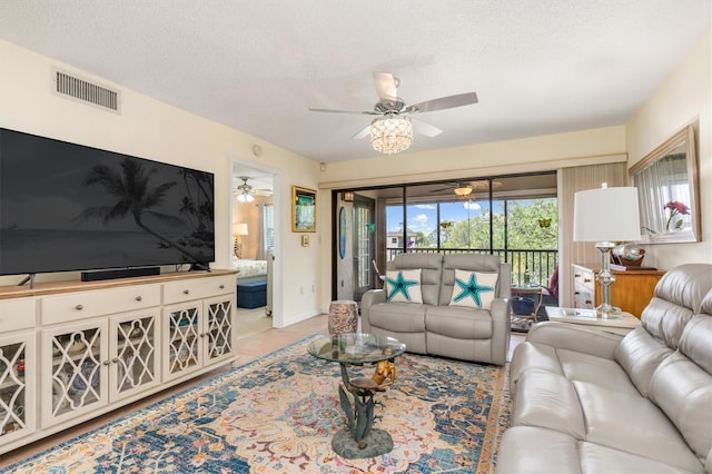 living area featuring ceiling fan, a textured ceiling, and visible vents