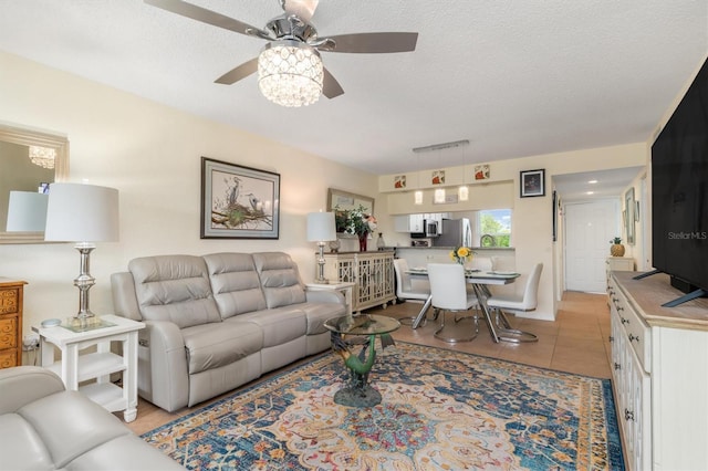 living room with light tile patterned floors, a ceiling fan, and a textured ceiling