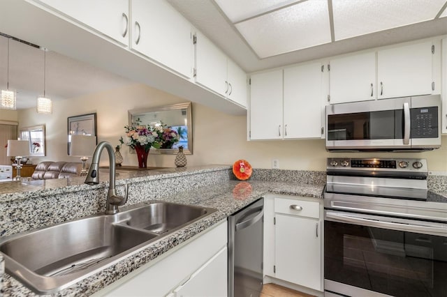 kitchen with a sink, white cabinetry, hanging light fixtures, and stainless steel appliances