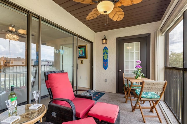 sunroom / solarium with carpet floors, ceiling fan, and a textured wall