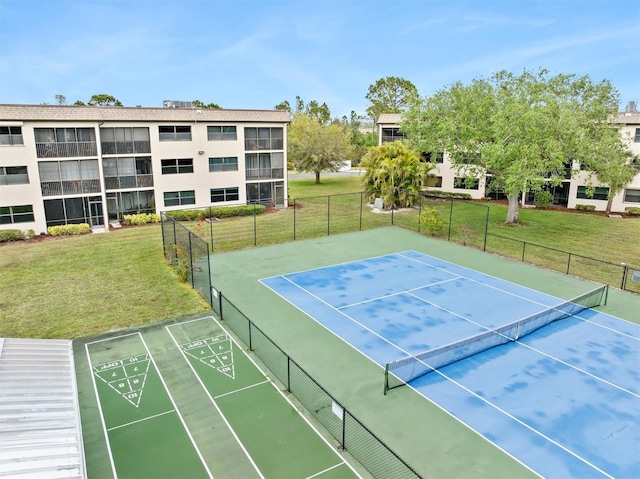 view of sport court with fence, a yard, and shuffleboard