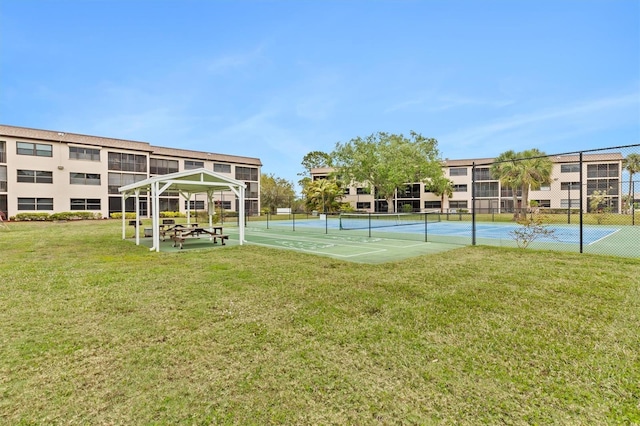 view of sport court with a lawn and fence