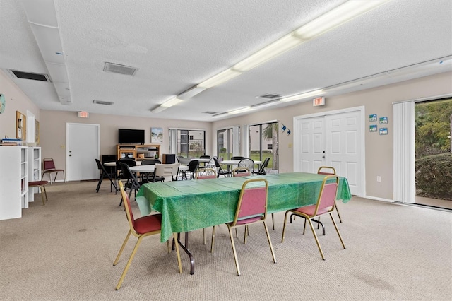 dining room with baseboards, light carpet, a textured ceiling, and visible vents