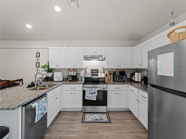 15579/15581 Chamberlain Blvd, Port Charlotte, FL 33953 - kitchen with appliances with stainless steel finishes, a sink, white cabinets, a peninsula, and under cabinet range hood