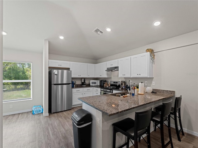 15579/15581 Chamberlain Blvd, Port Charlotte, FL 33953 - kitchen featuring visible vents, a peninsula, under cabinet range hood, a sink, and appliances with stainless steel finishes