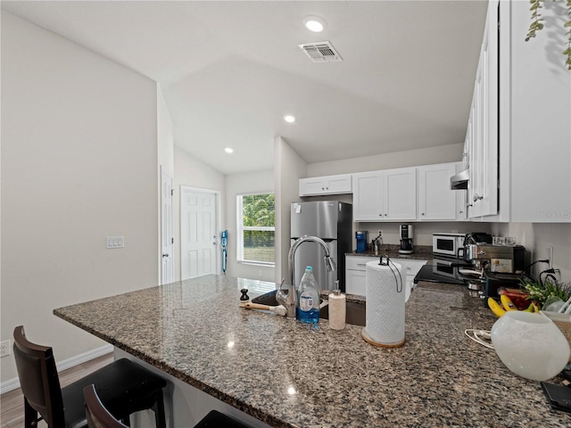 15579/15581 Chamberlain Blvd, Port Charlotte, FL 33953 - kitchen featuring a kitchen breakfast bar, freestanding refrigerator, a peninsula, lofted ceiling, and visible vents