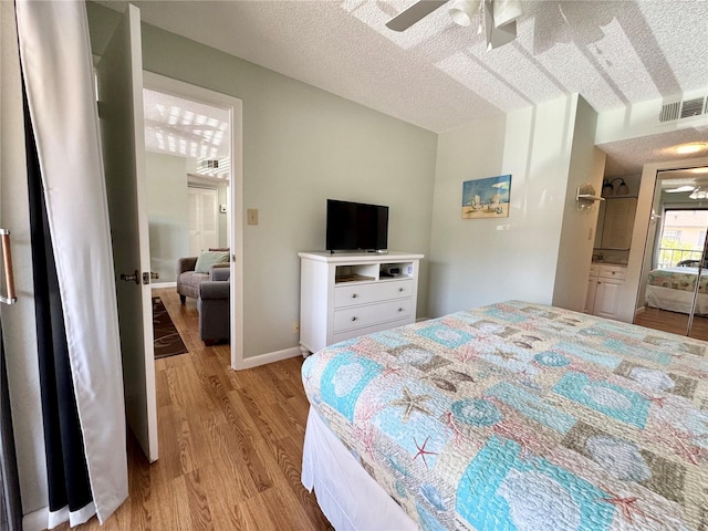 bedroom with a ceiling fan, light wood finished floors, a textured ceiling, and visible vents