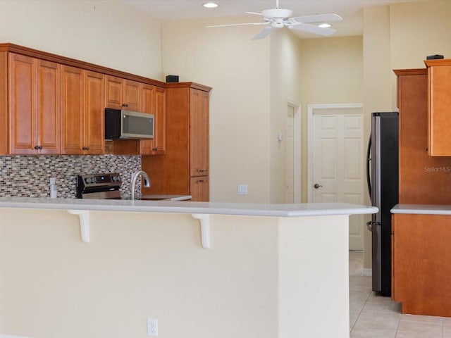 857 Macaw Cir, Venice, FL 34285 - kitchen with ceiling fan, a kitchen breakfast bar, a peninsula, and appliances with stainless steel finishes