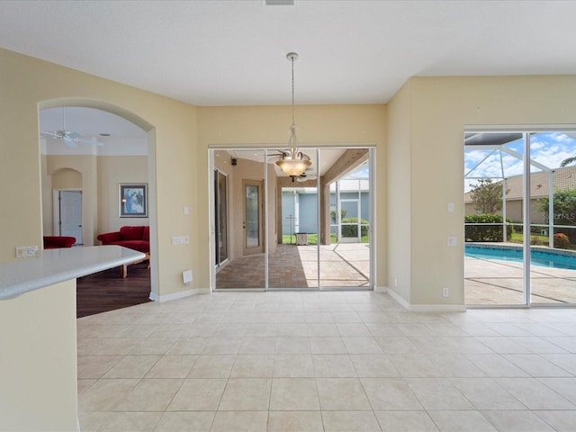 857 Macaw Cir, Venice, FL 34285 - unfurnished dining area featuring baseboards, light tile patterned flooring, a ceiling fan, and arched walkways