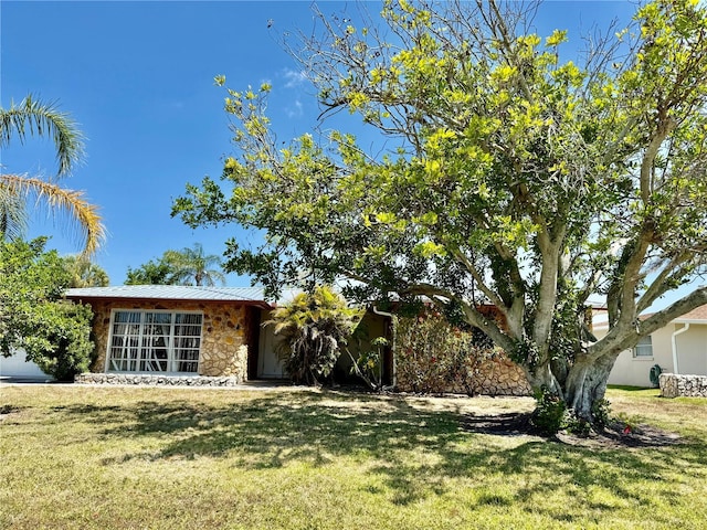 view of front of property with stone siding, metal roof, and a front yard