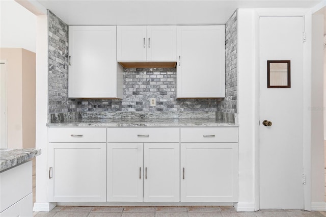 261 Caddy Rd, Rotonda West, FL 33947 - kitchen with backsplash, light stone countertops, and white cabinetry