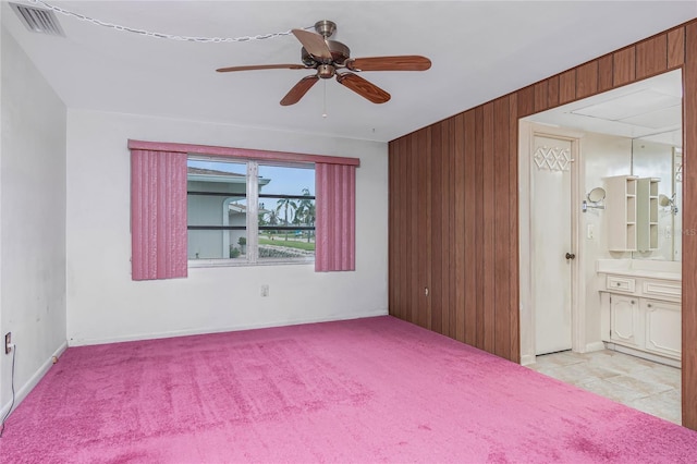 261 Caddy Rd, Rotonda West, FL 33947 - unfurnished bedroom with wooden walls, ensuite bath, a ceiling fan, and light colored carpet