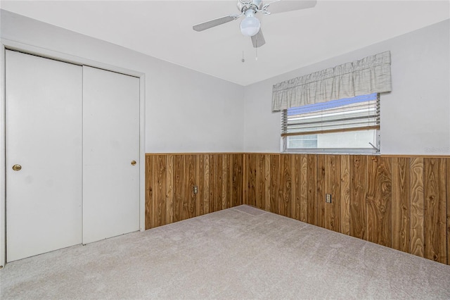 261 Caddy Rd, Rotonda West, FL 33947 - unfurnished bedroom with wooden walls, a wainscoted wall, carpet floors, a closet, and ceiling fan