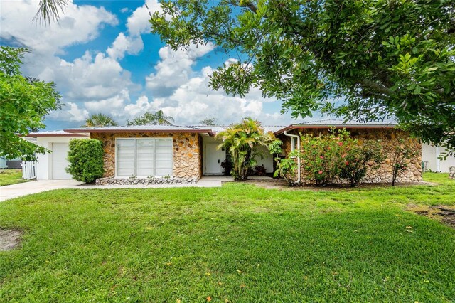 261 Caddy Rd, Rotonda West, FL 33947 - view of front facade with stone siding, an attached garage, a front yard, and driveway