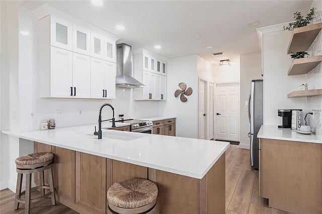 1711 Boca Raton Ct, Punta Gorda, FL 33950 - kitchen with light wood-style flooring, a peninsula, open shelves, a kitchen breakfast bar, and wall chimney range hood