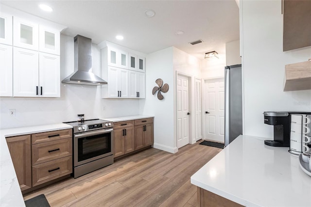 1711 Boca Raton Ct, Punta Gorda, FL 33950 - kitchen featuring light countertops, stainless steel appliances, white cabinetry, wall chimney range hood, and light wood-style floors