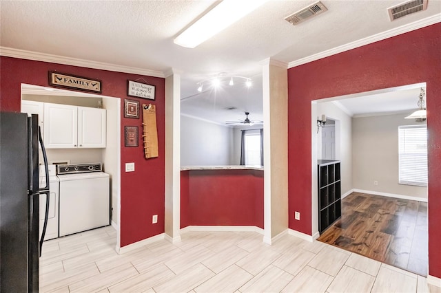 kitchen with visible vents, freestanding refrigerator, washer / dryer, and white cabinets