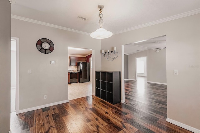 unfurnished dining area featuring dark wood-style flooring, baseboards, visible vents, and ornamental molding