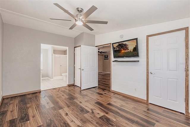 unfurnished bedroom with a ceiling fan, baseboards, wood finished floors, and ensuite bathroom